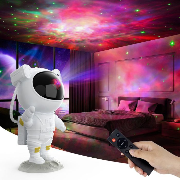 Astronaut galaxy projector in a bedroom, pink and green nebula on the ceiling, remote in hand